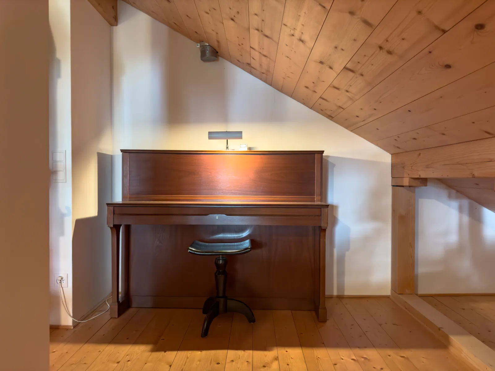 Klavier unter der geneigten Holzdecke im Dachgeschoss