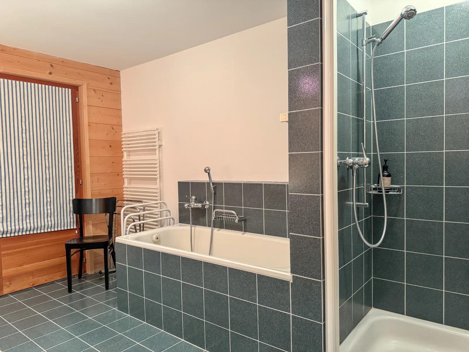 Bad mit Badewanne und separater Dusche, grün gekachelt, die Wände in Lärche getäfert