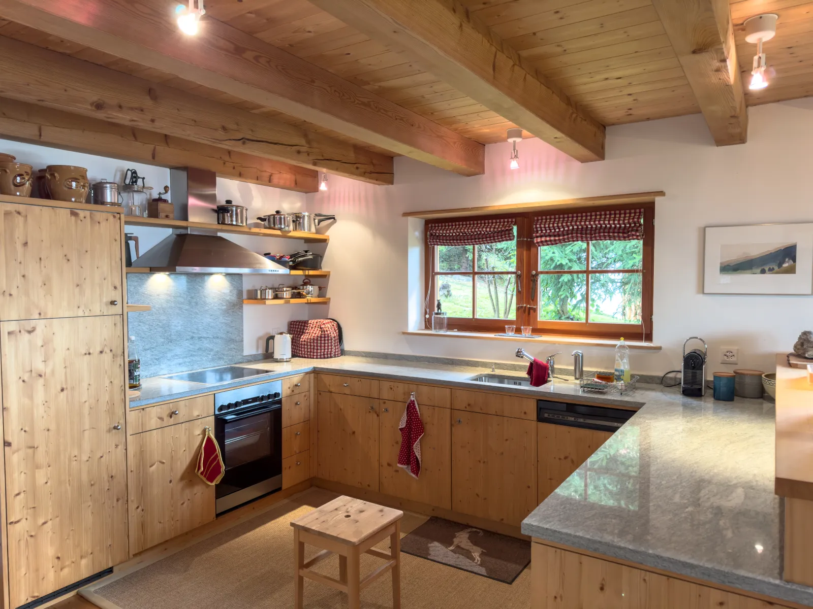 Küche mit Steinabdeckungen, Backofen, Dampfabzug und offenen Regalen, das Fenster geht in den Garten