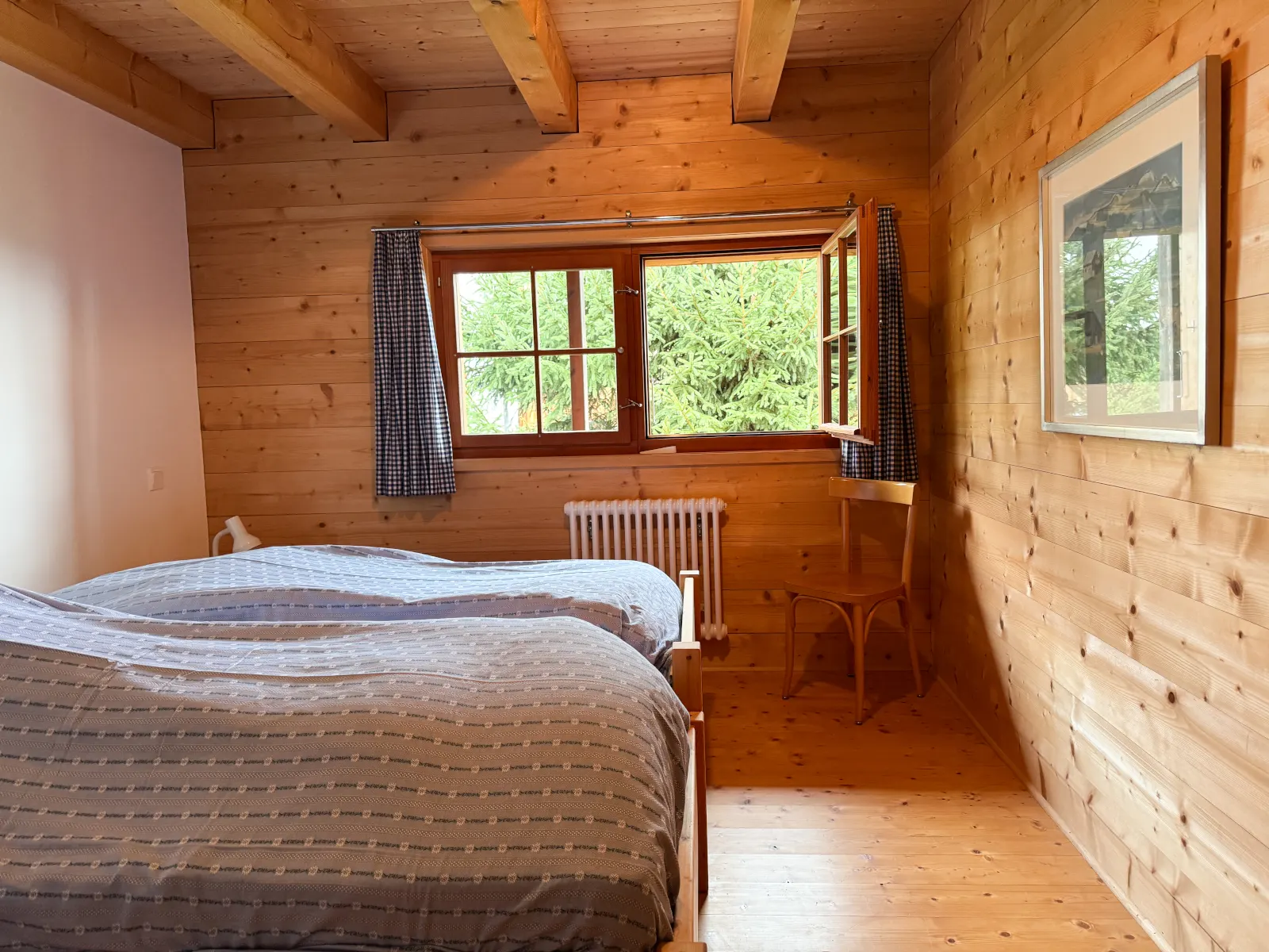 Schlafzimmer mit zwei Betten und offenem Fenster zu den Fichten im Garten