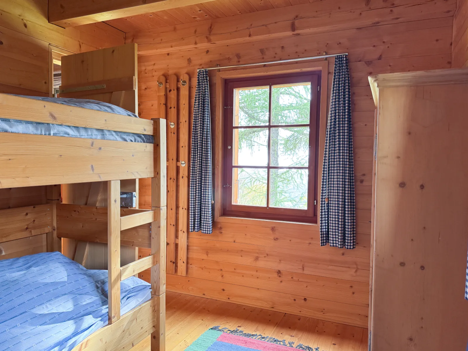 Kinderzimmer mit Kajütenbett, Lärchenholz und blau-karierten Vorhängen